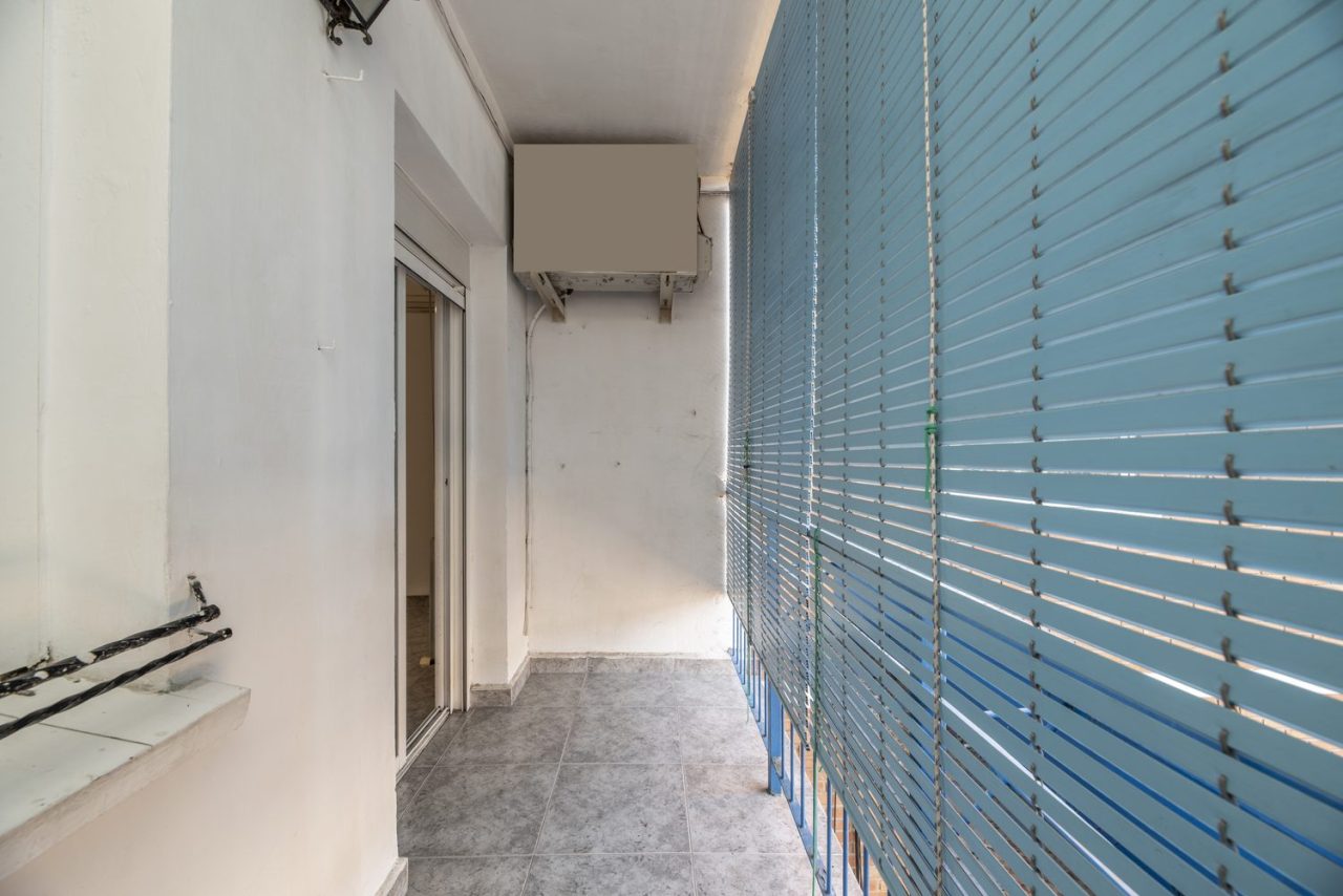 Salon étroit aménagé avec un canapé compact et un passage dégagé vers le balcon.