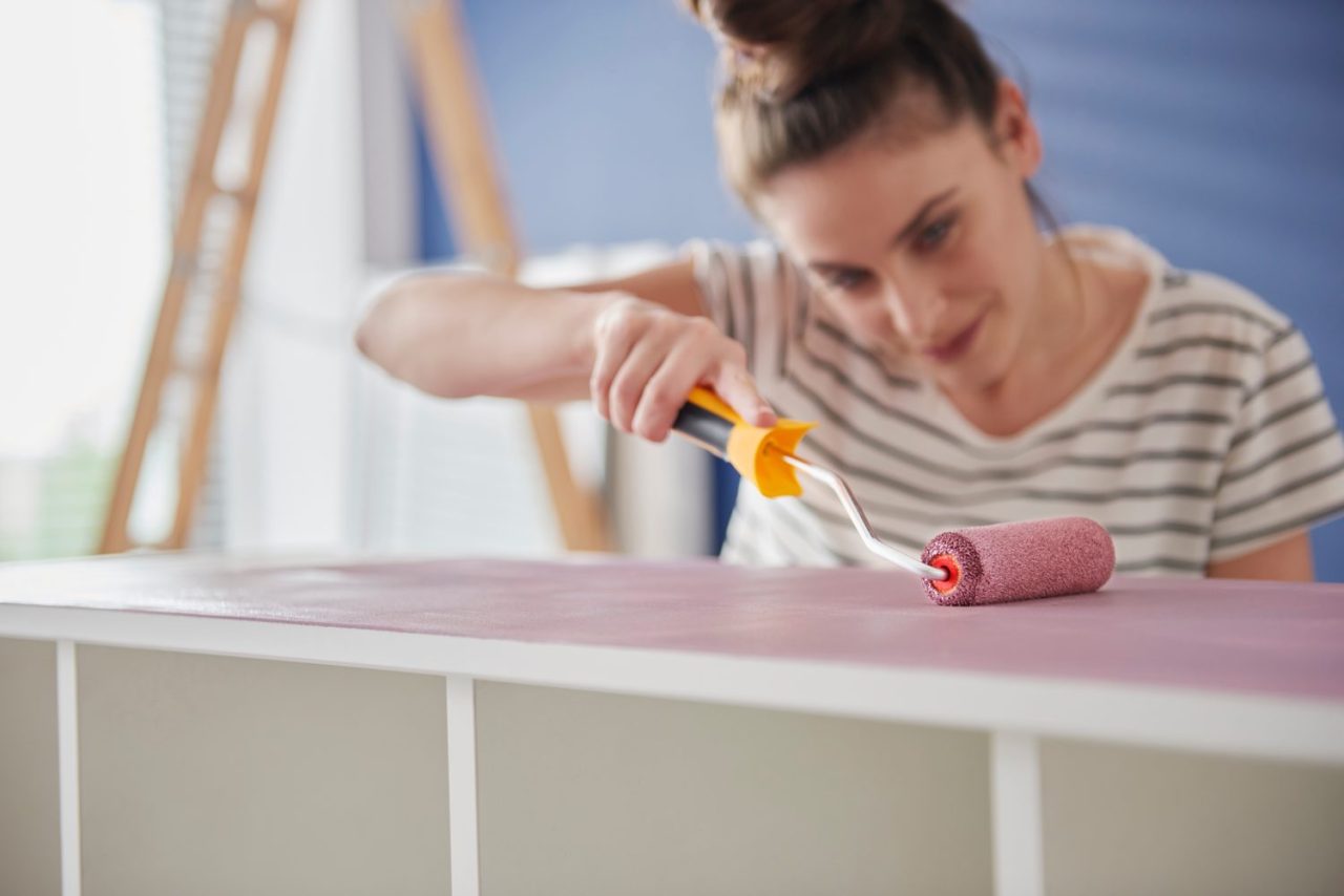 Personne appliquant de la peinture sur un plan de travail de cuisine avec un rouleau